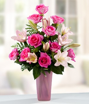 arreglo de rosas rosadas y lirios rosados en florero de cristal